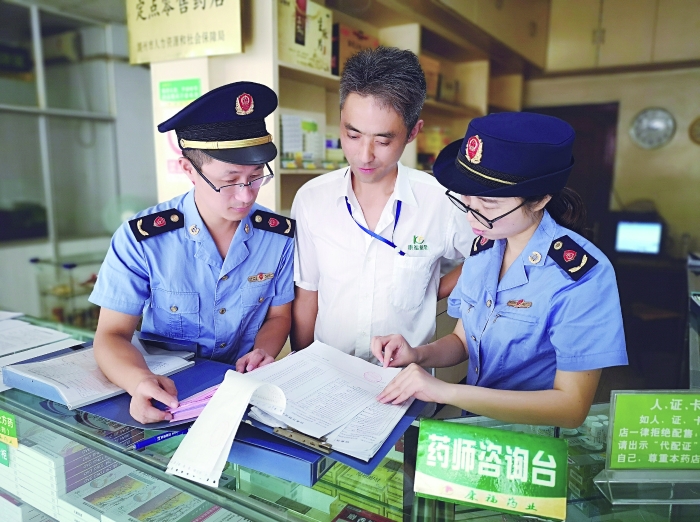 執(zhí)法人員在一家藥店檢查特殊藥品進貨臺賬。