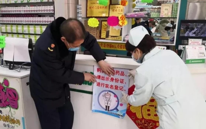 赤峰市紅山區(qū)市場監(jiān)管局監(jiān)管人員正在藥店張貼“實名登記購買退燒藥”宣傳海報。（赤峰市市場監(jiān)管局供圖）