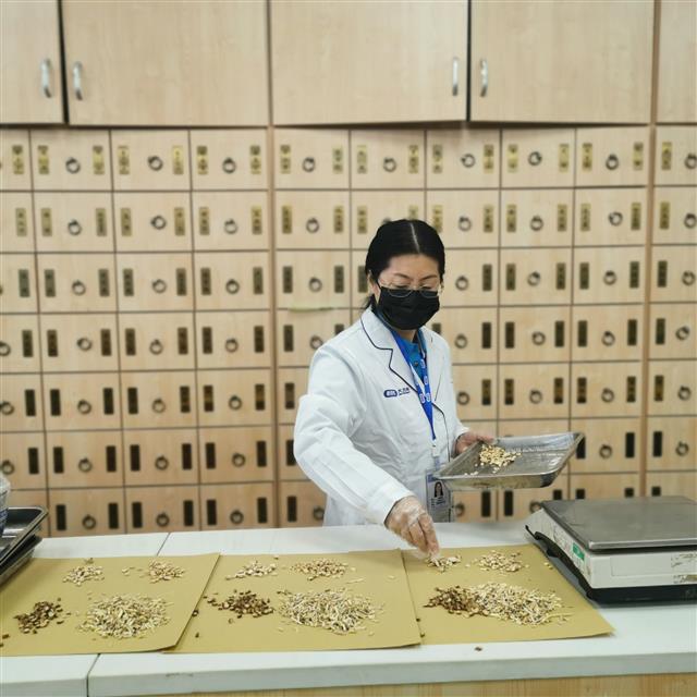 　侯惠鳴為顧客抓藥。