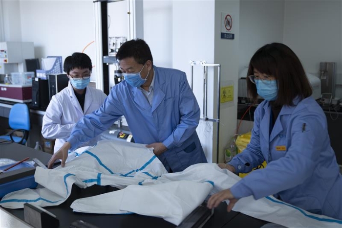 圖為趙玉杰（中）檢查醫(yī)用防護服應(yīng)急檢測工作。