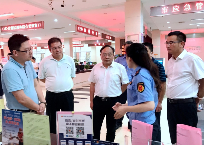 上官新晨（左三）在鷹潭市行政服務(wù)中心詳細(xì)了解“一照含證”改革情況。