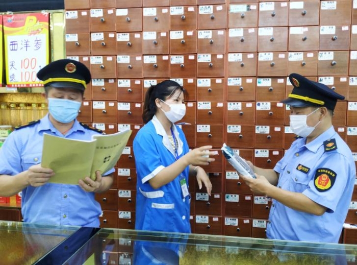 圖為執(zhí)法人員在一家零售藥店檢查中藥飲片進貨臺賬、質(zhì)量安全等情況。