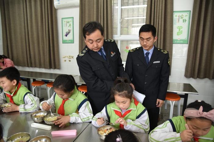 圖為執(zhí)法人員檢查食堂食品安全情況。