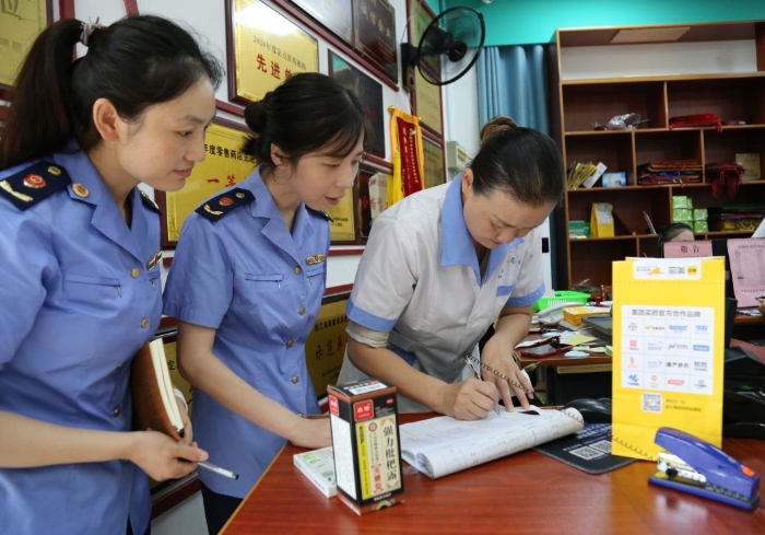 圖為執(zhí)法人員查看網(wǎng)絡(luò)藥品銷售登記，核對處方藥處方單。