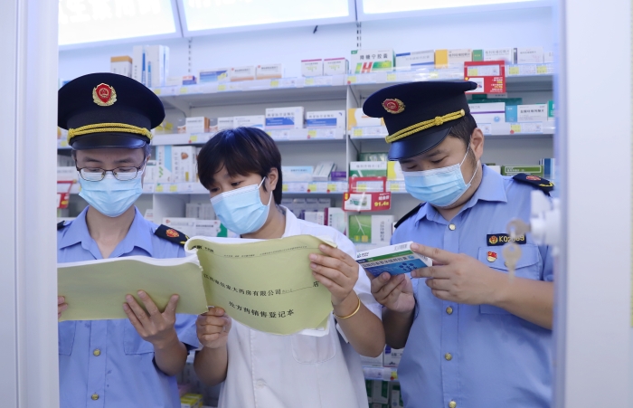 圖為9月13日執(zhí)法人員在一家藥店查看網(wǎng)絡(luò)藥品銷售登記情況，并核對處方藥處方單。