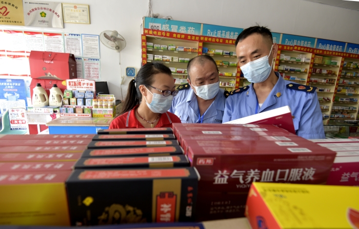 圖為執(zhí)法人員在一家藥店檢查中成藥質(zhì)量。