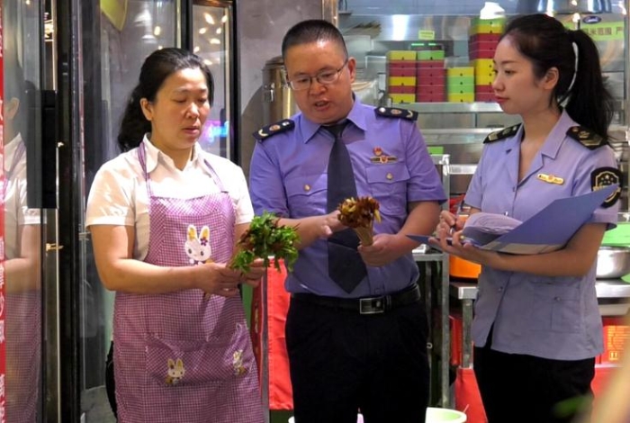 圖為執(zhí)法人員在一火鍋店檢查火鍋食品原輔材料進(jìn)貨情況。