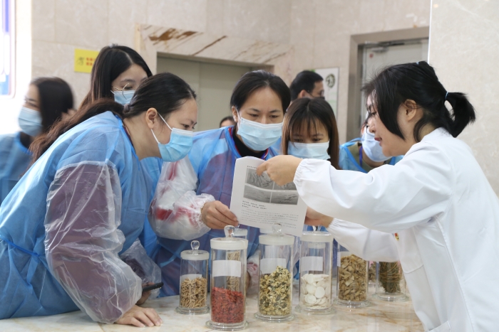 圖為工作人員為市民代表講解中藥材真?zhèn)舞b別知識(shí)。