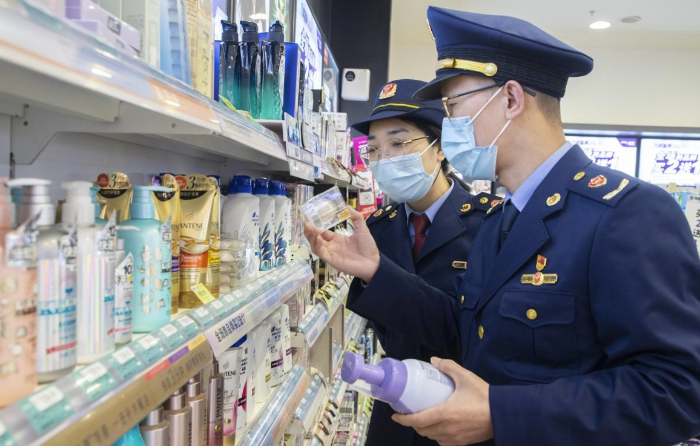 圖為執(zhí)法人員在超市化妝品專柜檢查化妝品標(biāo)簽標(biāo)識情形。