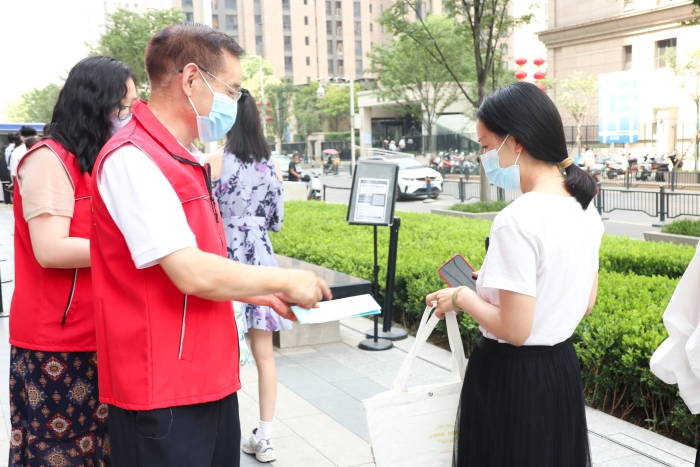 圖為藥監(jiān)系統(tǒng)志愿者為排隊等待檢測的居民發(fā)放科普抗疫小禮包，并為居民開展藥品安全科普，耐心解答居民用藥、用械安全方面的疑問和咨詢。（郝曉靜攝）
