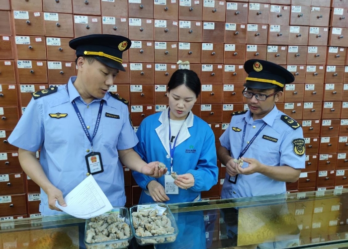 圖為執(zhí)法人員在一零售藥店檢查中藥飲片質(zhì)量情況。