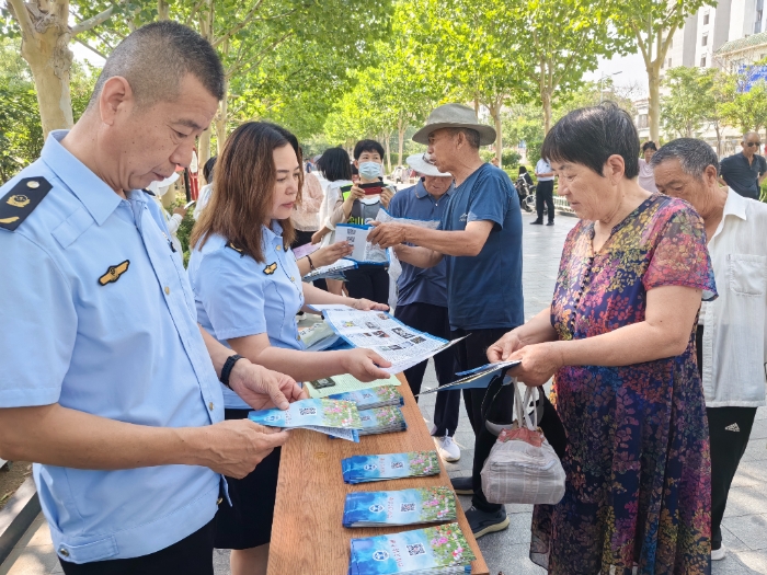 圖為工作人員向群眾發(fā)放禁毒宣傳手冊(cè)。